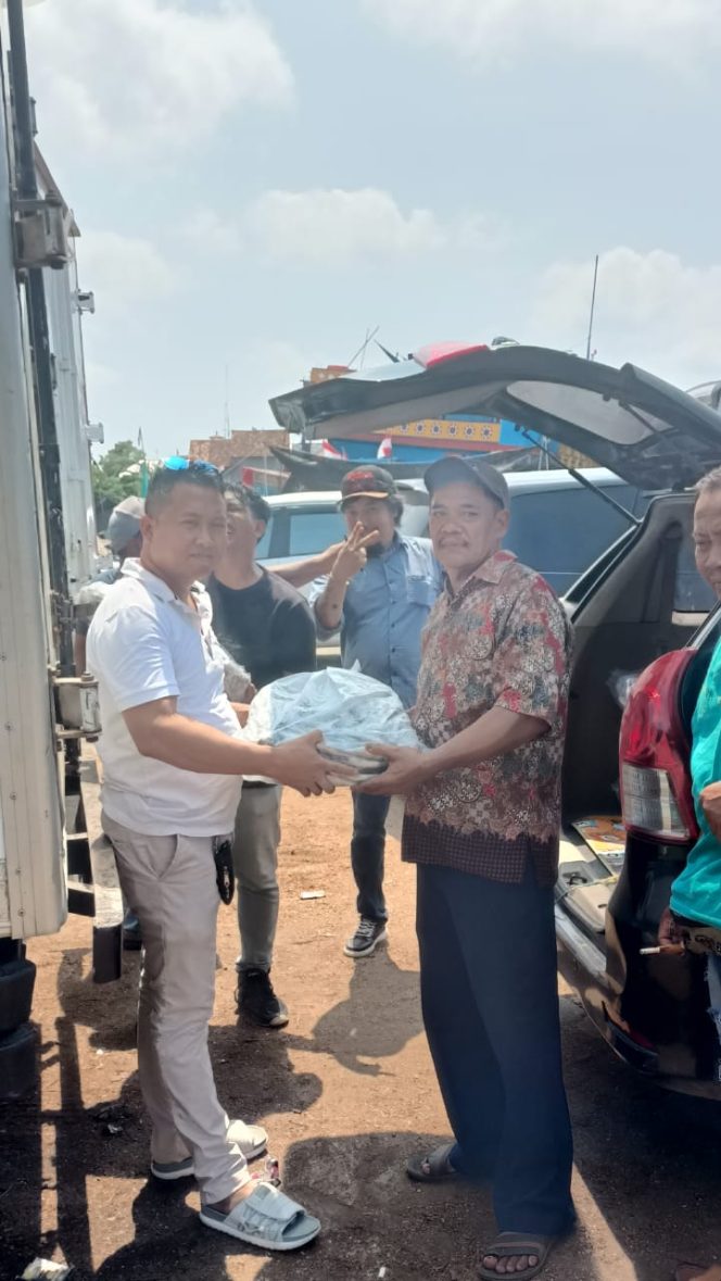 
					Caleg DPRD Pati Dapil 3 dari Partai Demokrat, Mukit (kiri) membagikan ikan kepada masyarakat yang juga timsesnya sebagai bentuk kepedulian