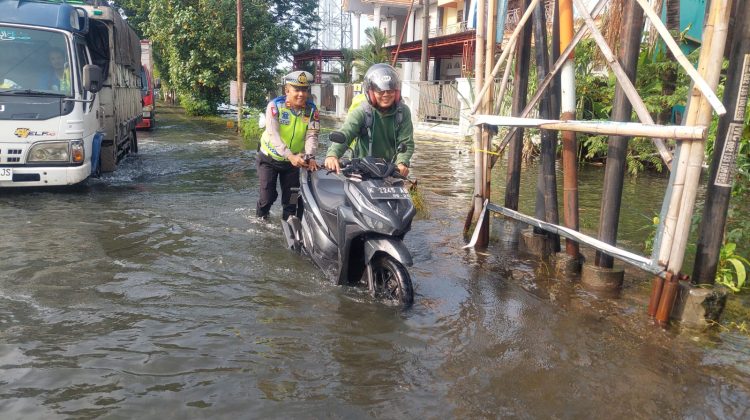 KBO Satlantas Polres Kudus, Iptu Noor Alifi membantu mendorong sepeda motor pengendara yang mogok karena banjir


