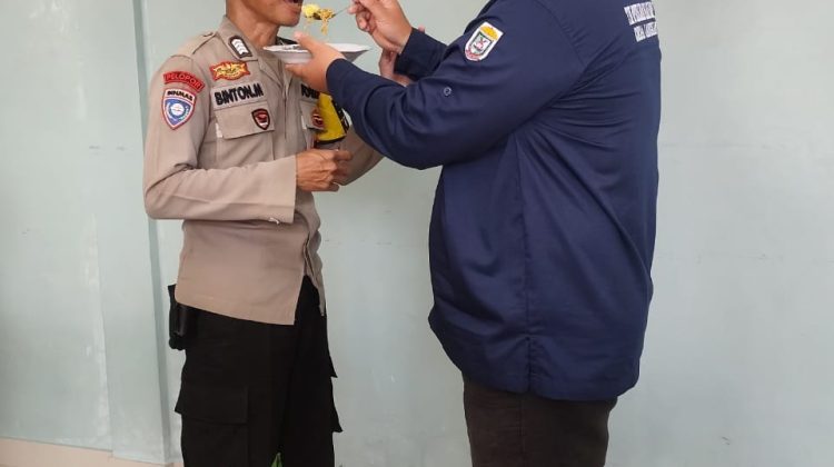 Bhabinkamtibmas Desa Langkan, Bripka Binton Manurung menerima suapan nasi tumpeng dari Kades, Muhammad Yaser Irma. foto:anr
